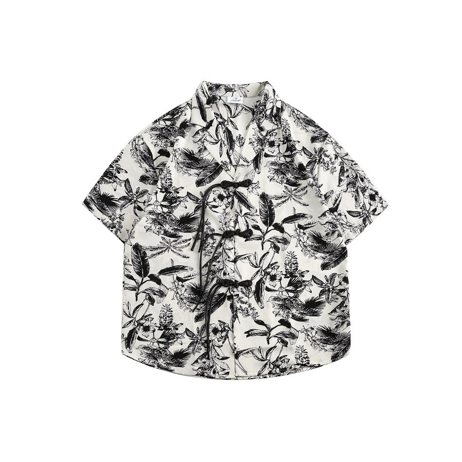 Black and white botanical print short-sleeve shirt with knotted frog button closure, front flat lay