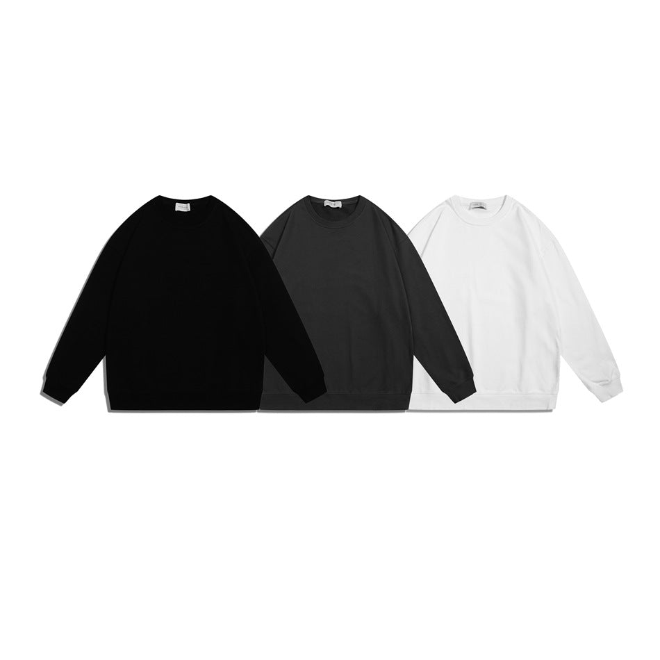 Three plain crewneck sweatshirts shown together in black, charcoal gray, and white.