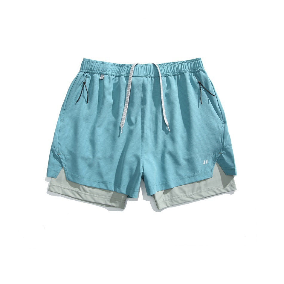 Blue double-layer athletic shorts with light gray-green inner layer, drawcord and zip pockets, flat lay