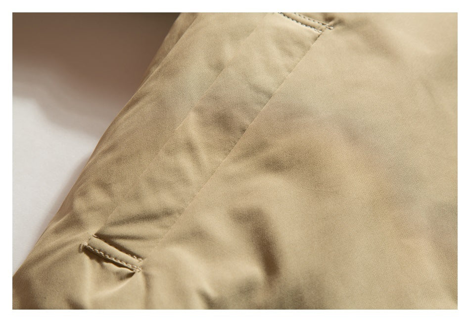 Close-up of tan jacket fabric, a seam, and a small stitched slit detail.