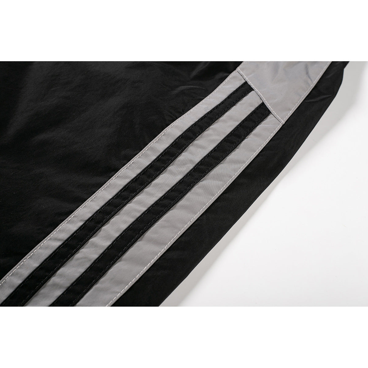 Close-up of black shorts with a broad gray side stripe and two narrow black bands.