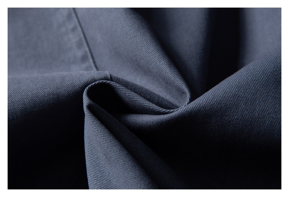 Close-up of dark blue-gray fabric folded to show its fine diagonal texture.