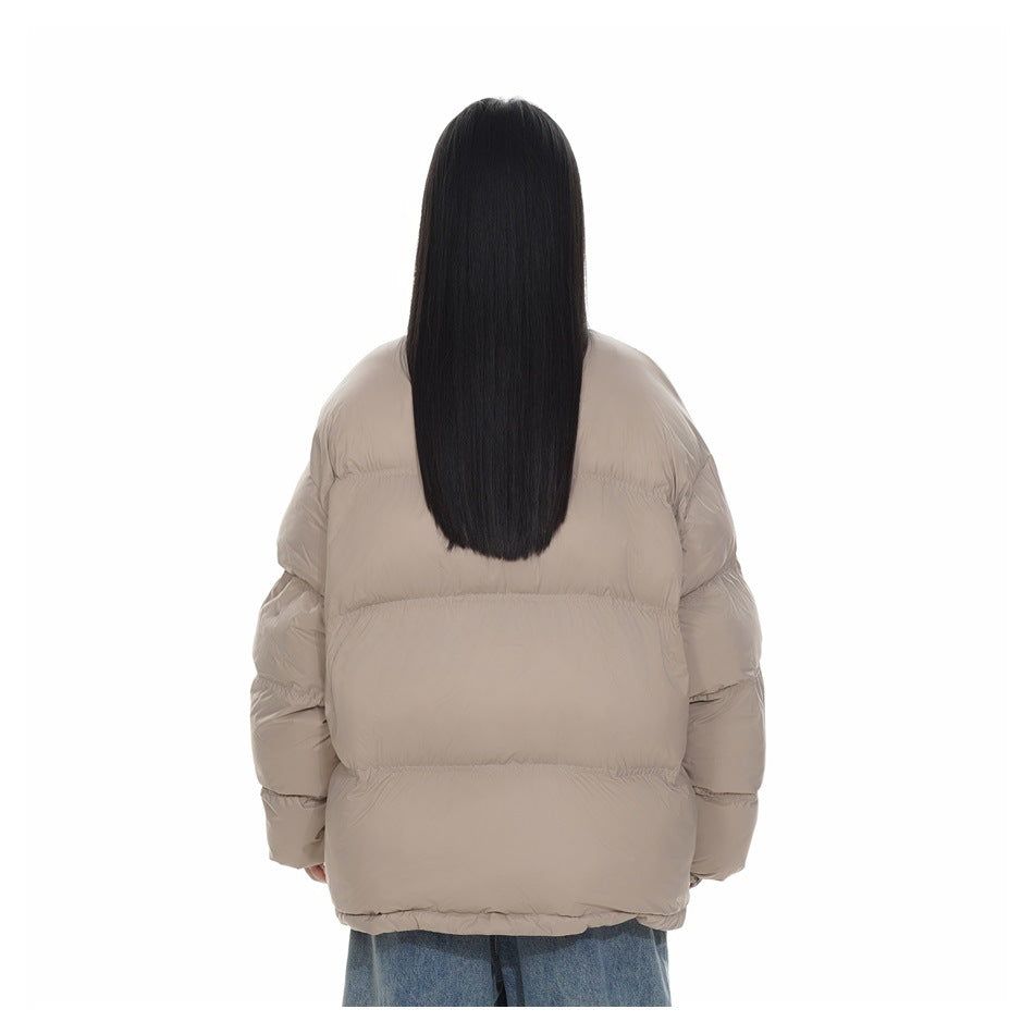 Rear view of a model wearing a taupe quilted puffer jacket with blue jeans.