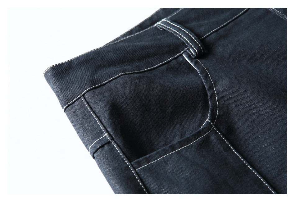 Close-up of a dark indigo trouser front pocket and belt loop with white contrast stitching.