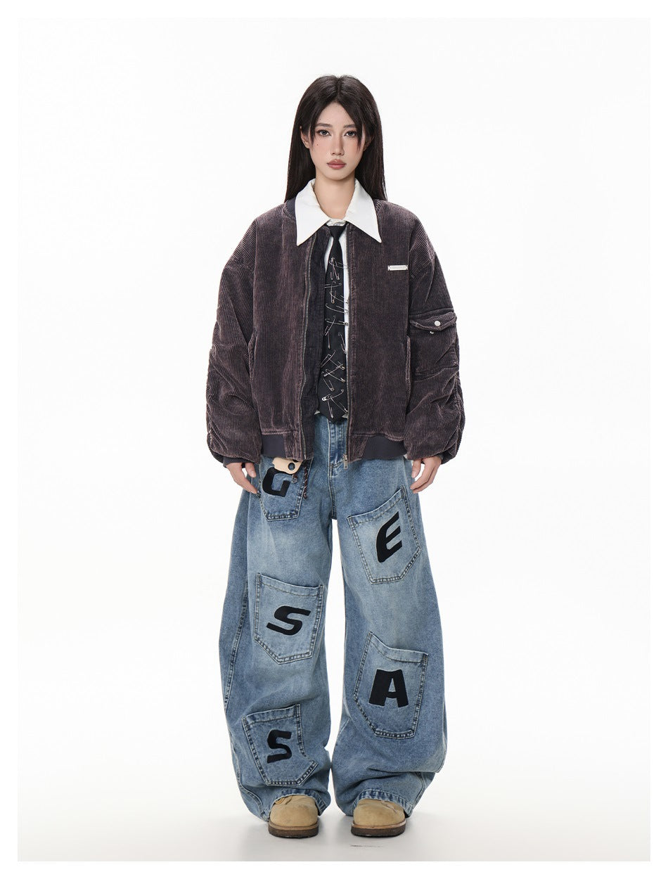 Model wearing open dark purple-gray corduroy bomber jacket over white shirt and tie with wide-leg jeans, full-length view