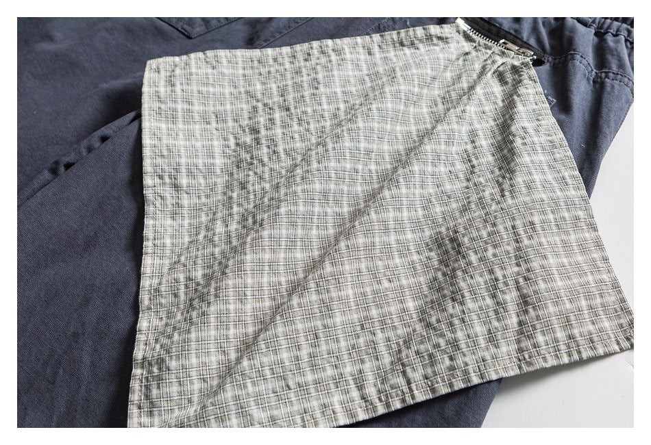 Beige plaid pocket lining laid over dark shorts, showing the contrasting pattern and stitching.