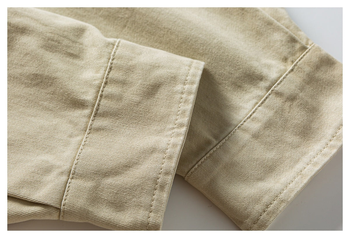 Close-up of beige twill jacket sleeve fabric and stitched cuff seam.