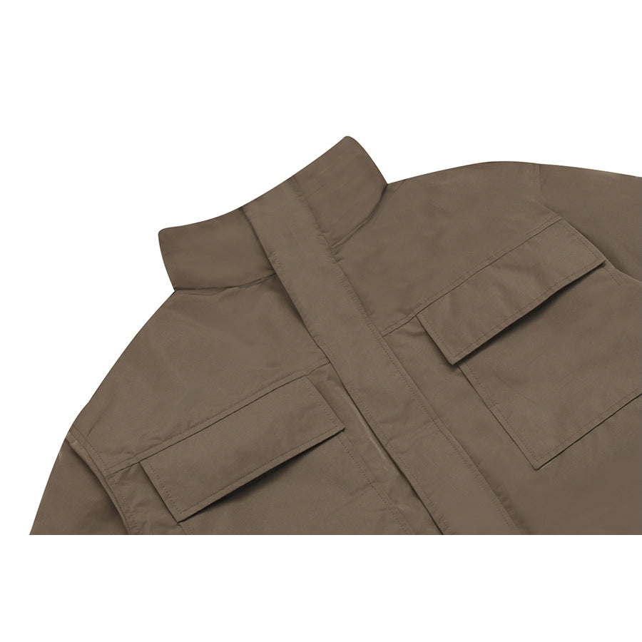 Close-up of a brown jacket's stand collar and two flap chest pockets.
