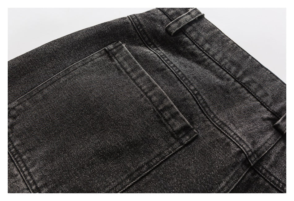 Close-up of a rear pocket and waistband seam on charcoal washed jeans.