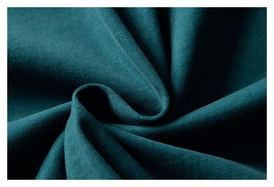 Close-up of dark teal fabric draped into soft folds, showing its fine knit texture.