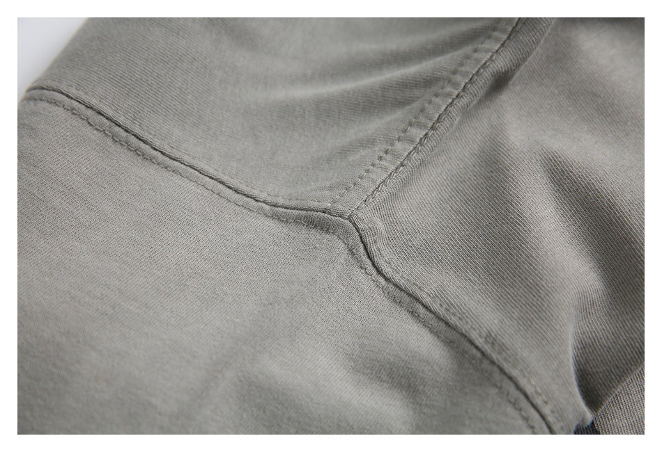 Close-up of stitching and panel seams on a plain light gray garment.