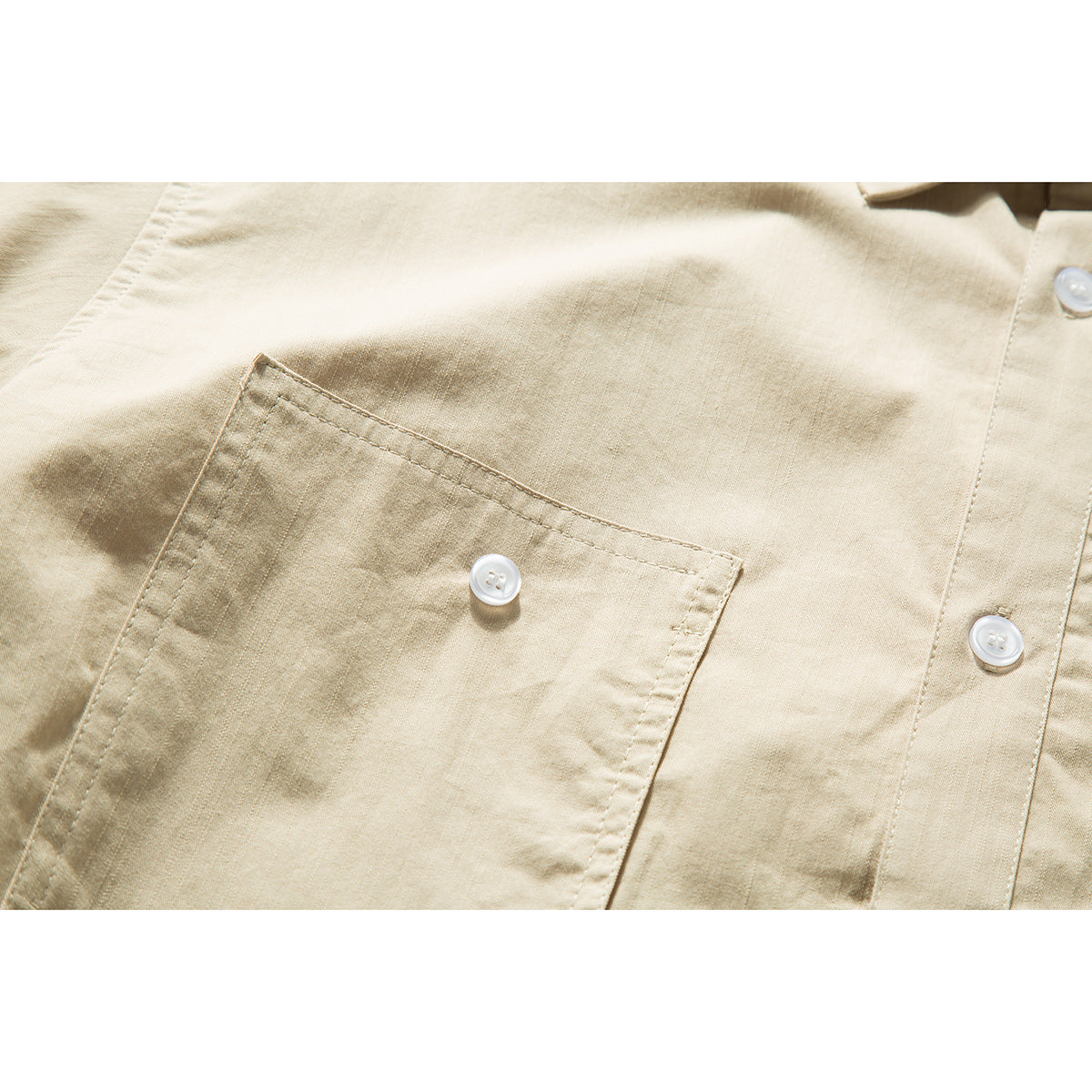 Close-up of a beige shirt’s buttoned chest pocket and front placket.