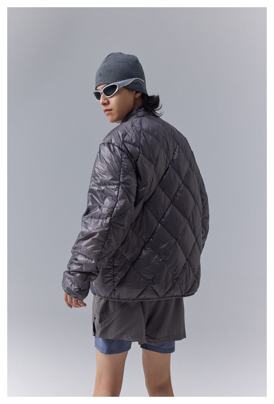 Model showing the back of a charcoal gray quilted jacket with diagonal diamond stitching.