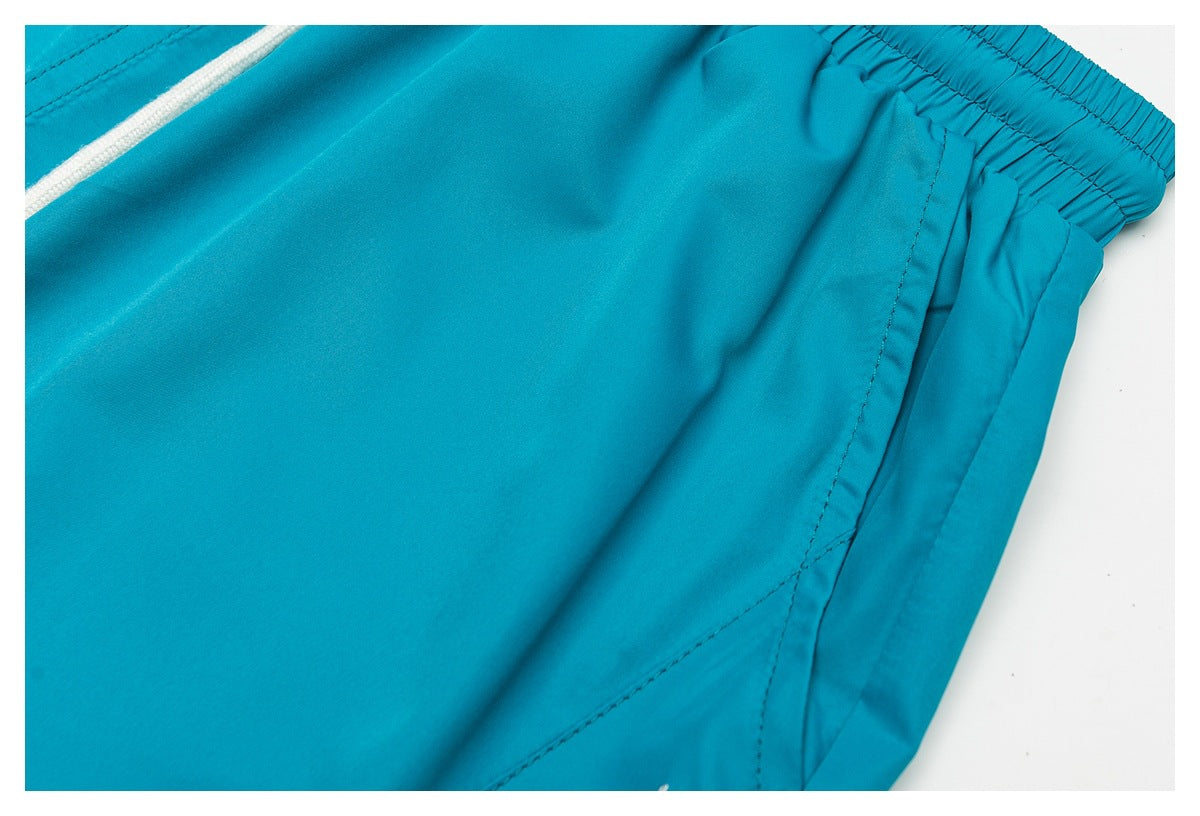 Close-up of turquoise shorts showing the gathered elastic waistband and curved side pocket seam.