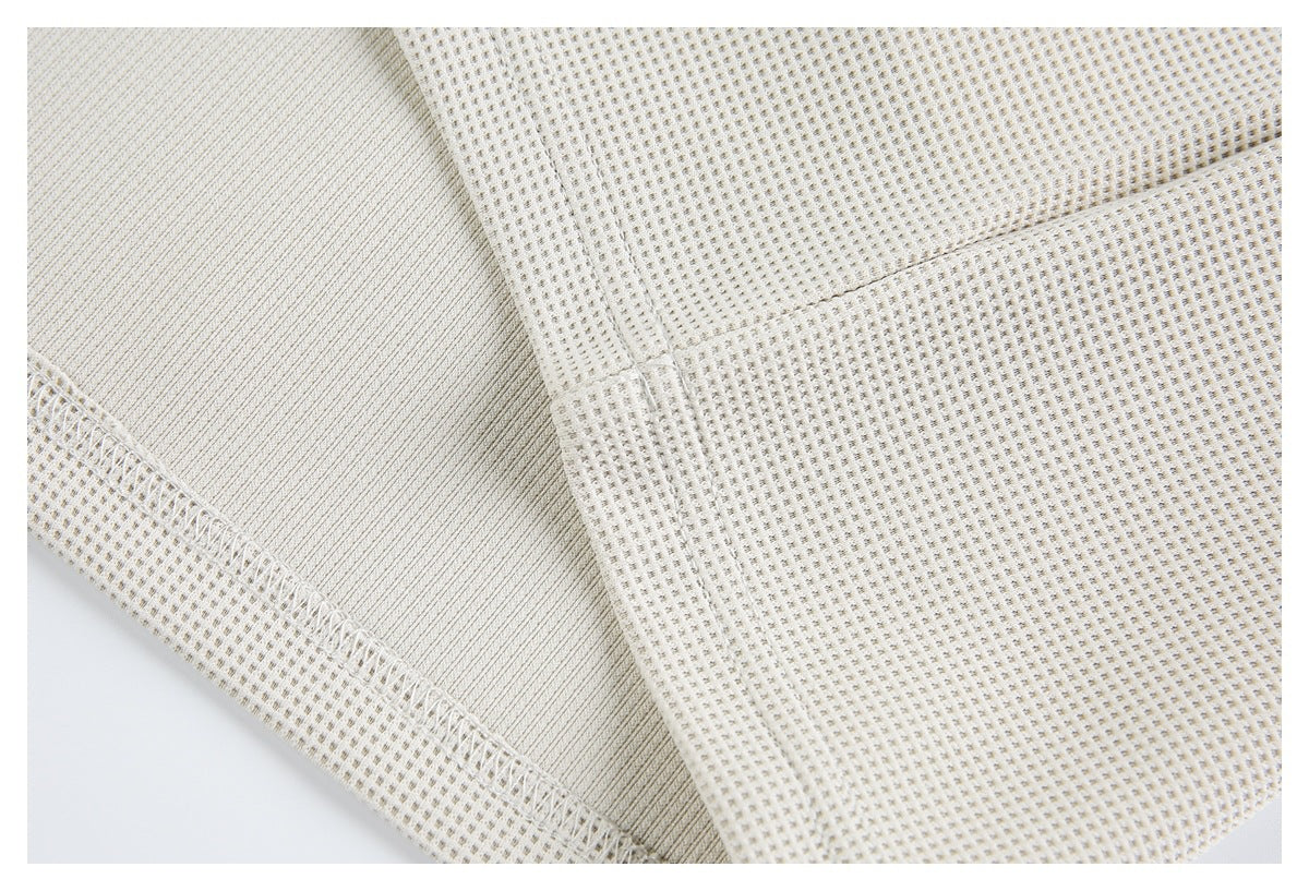 Close-up of the off-white shirt's textured fabric, inner seam, and overlocked stitching.