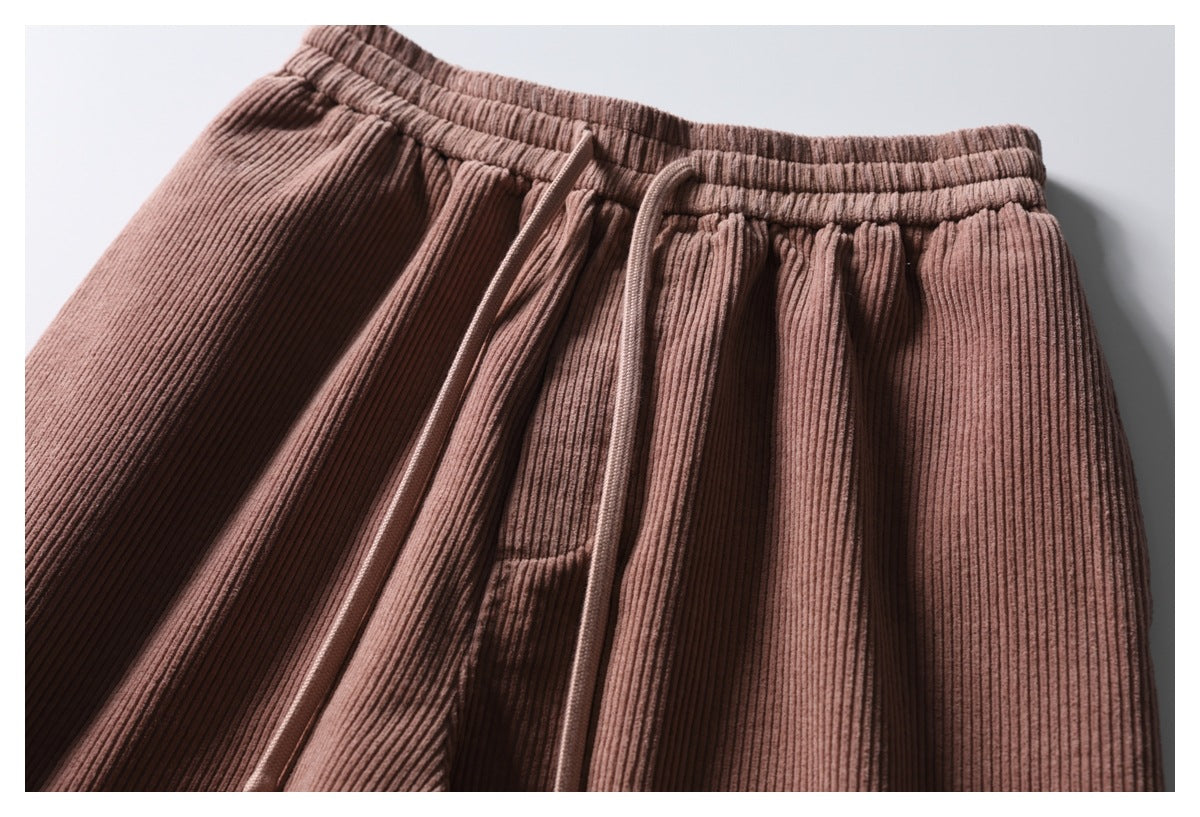 Close-up of dusty rose ribbed trousers showing an elastic waistband, front pleats, and drawstrings.