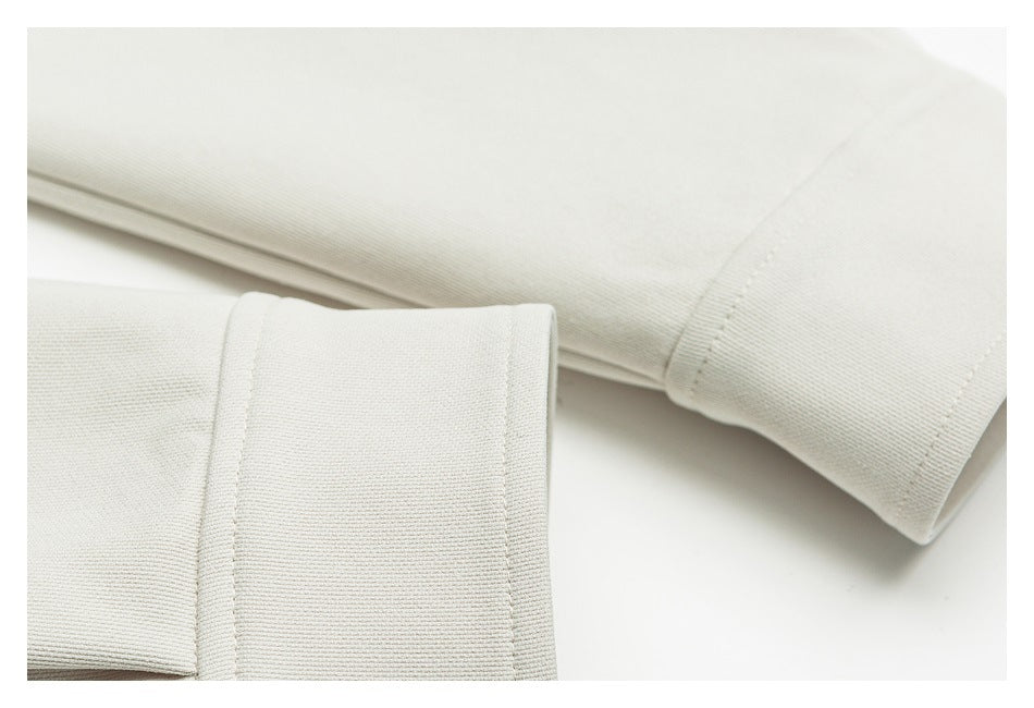Close-up of off-white garment cuffs and neatly stitched edges.