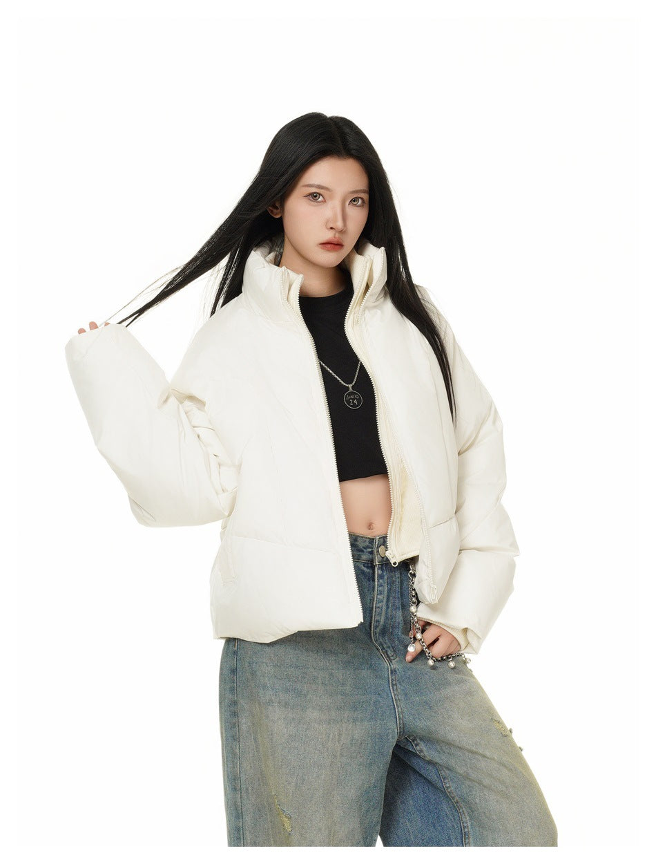 Model posing in an open ivory cropped puffer jacket with a high collar and voluminous sleeves.