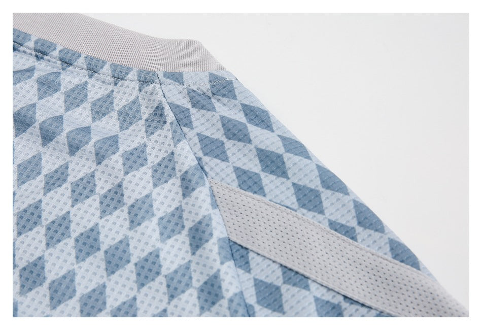 Close-up of a blue geometric-print garment showing a ribbed light gray edge, seam, and perforated mesh insert.