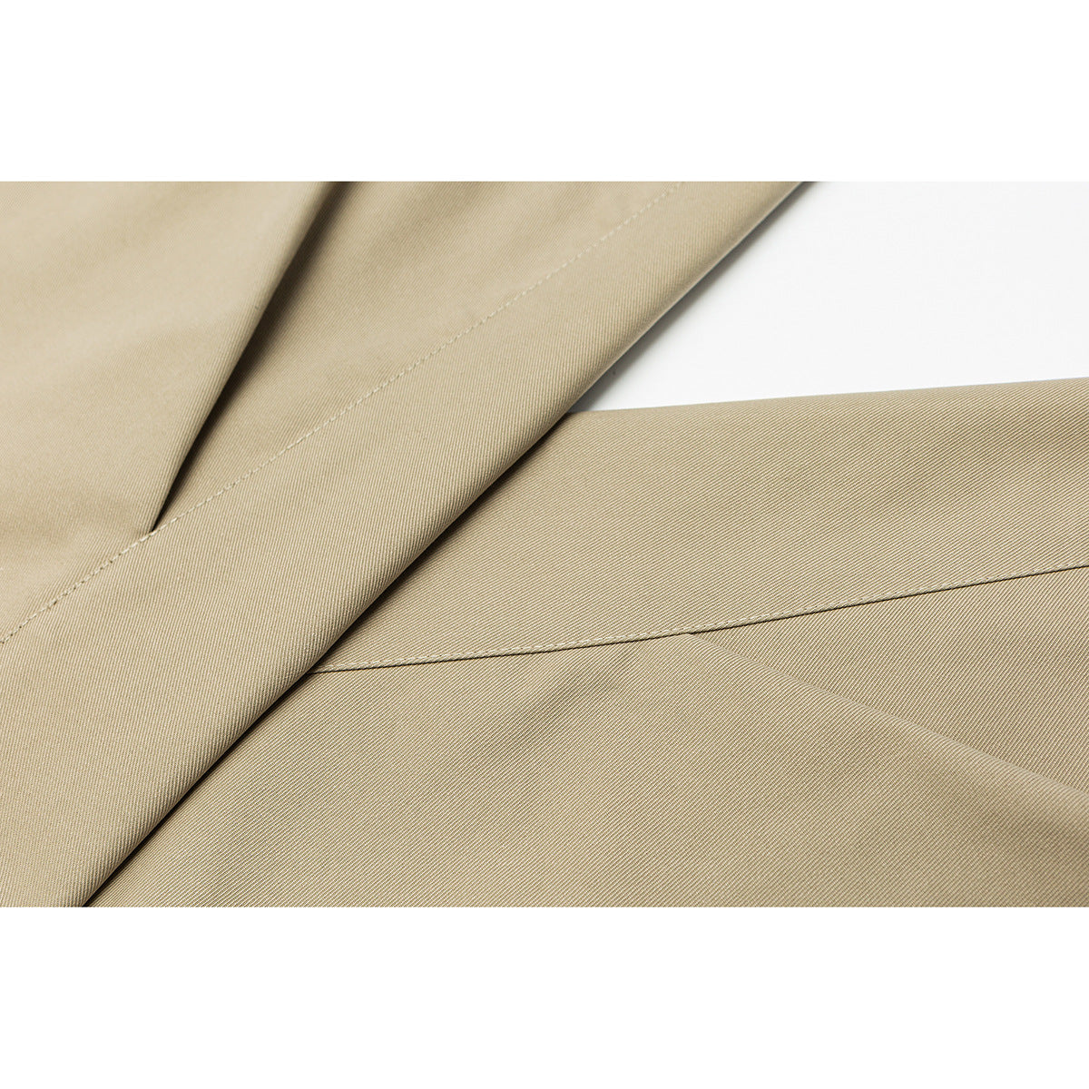 Close-up of beige trouser fabric with fine diagonal texture and stitched seams.