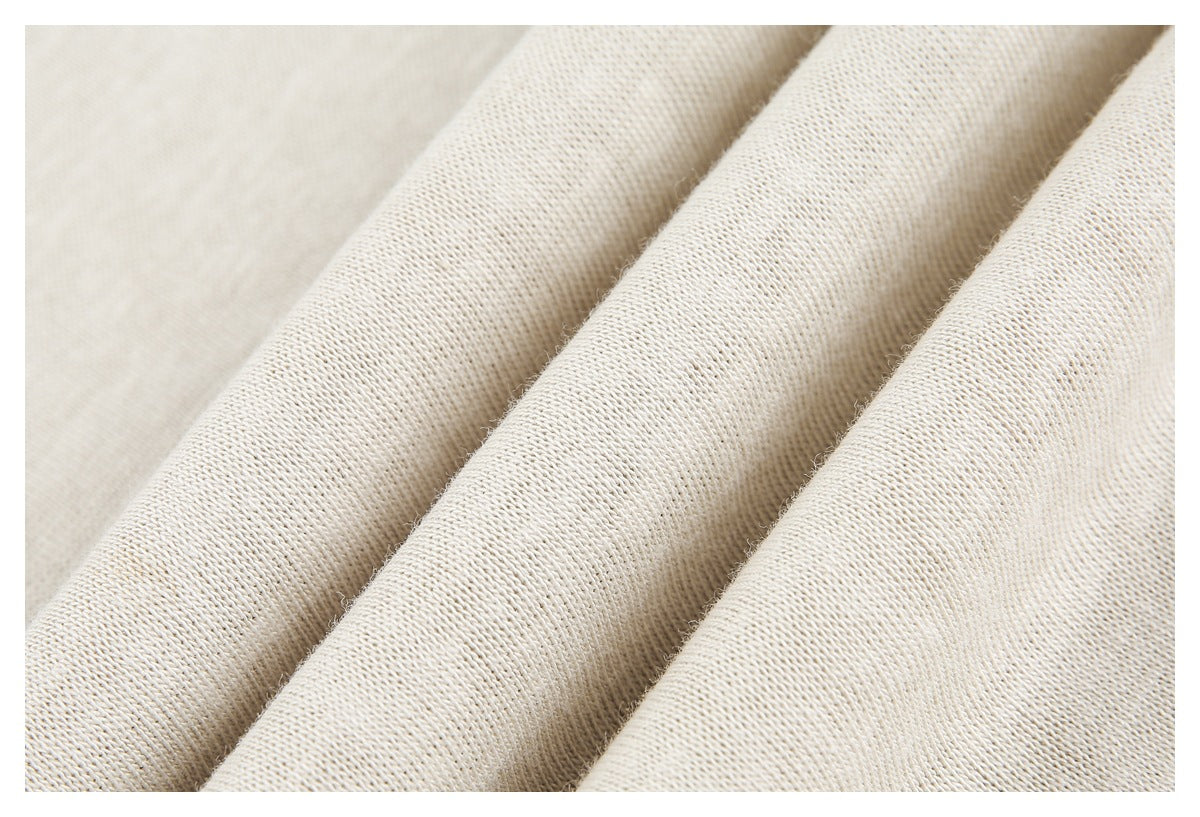 Close-up of cream knit fabric draped in soft folds, showing its fine surface texture.