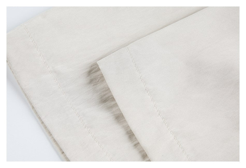 Close-up of overlapping light beige garment panels with visible stitching.