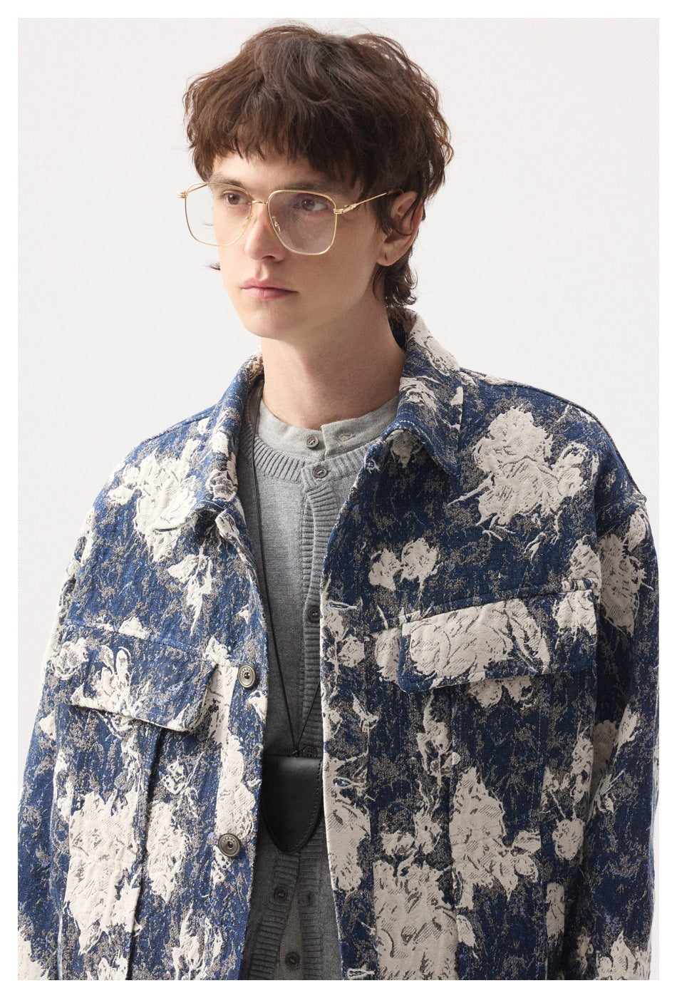 Close view of a model wearing a blue and cream floral button jacket with flap chest pockets.