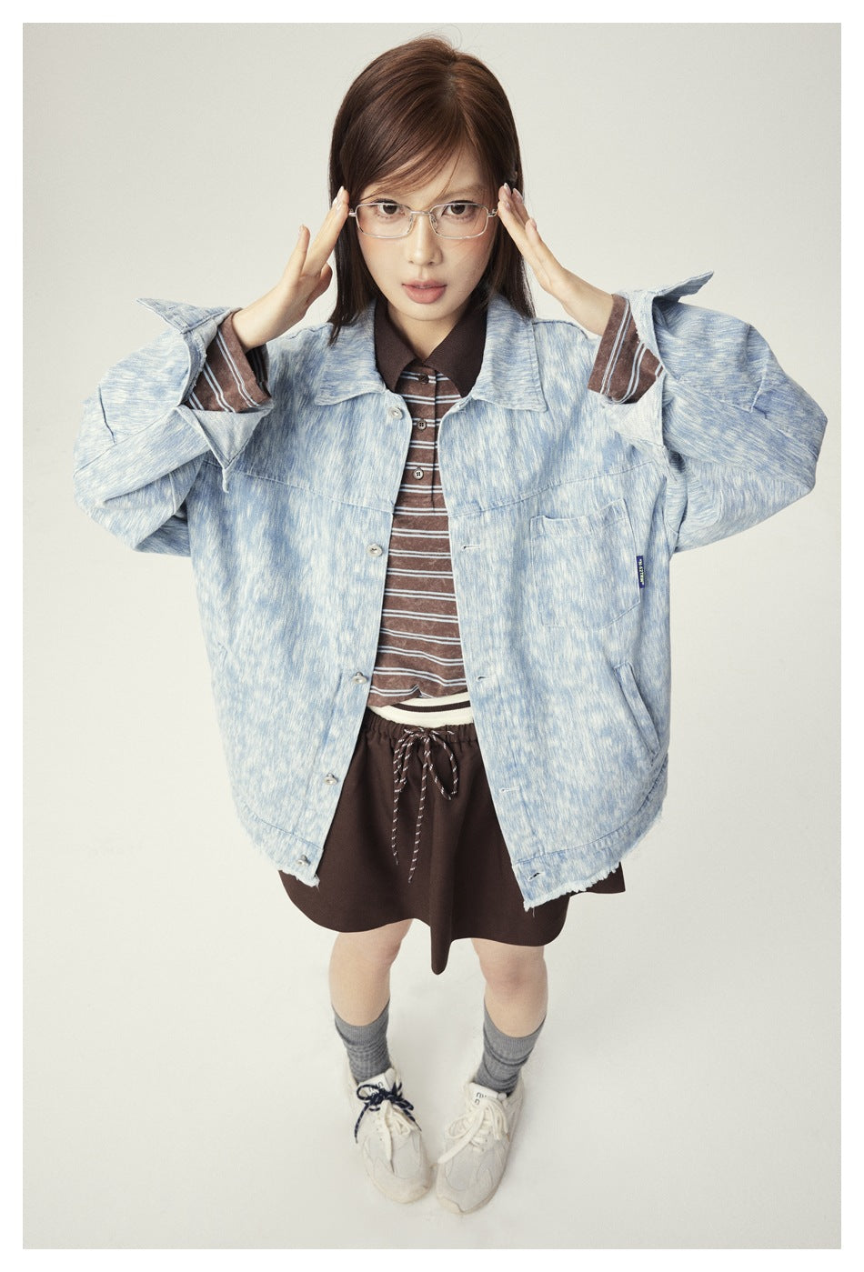 Close front view of a model wearing a pale blue mottled jacket with wide sleeves and a button front.