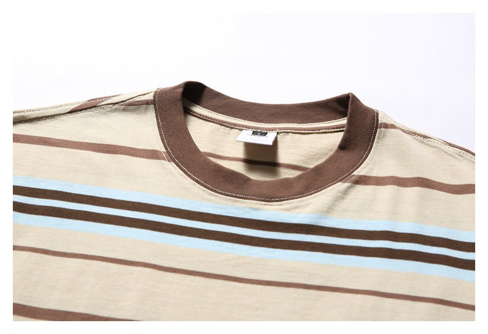 Close-up of a beige T-shirt with a brown ribbed crew neck and horizontal brown and pale blue stripes.