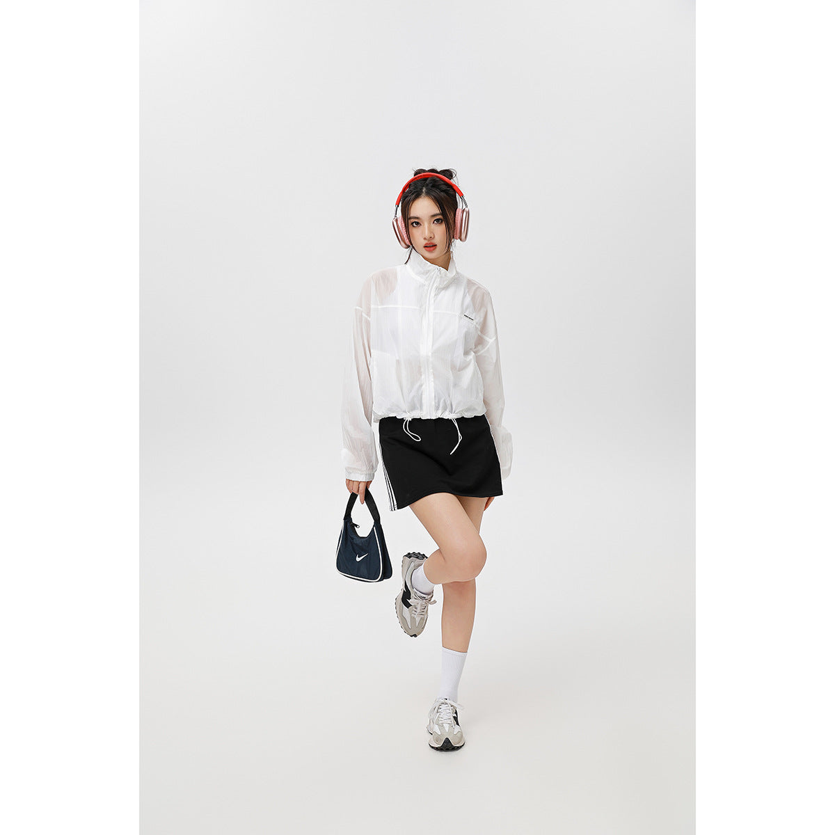 Model wearing a white sheer-looking zip-up jacket with a high collar and drawstring hem.