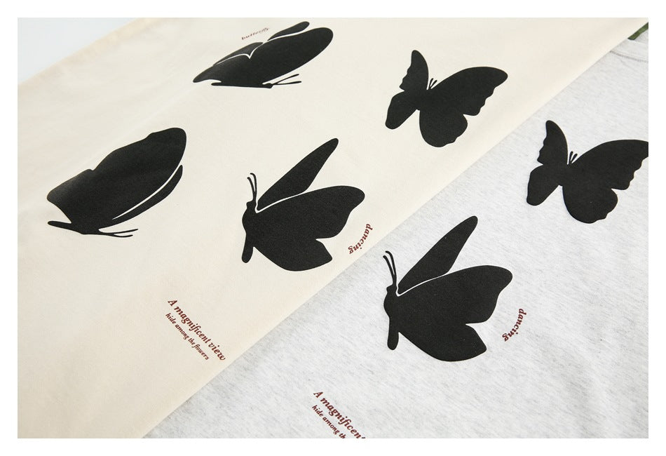 Close-up of cream and light gray shirt fabric with black butterfly prints and small brown English text.