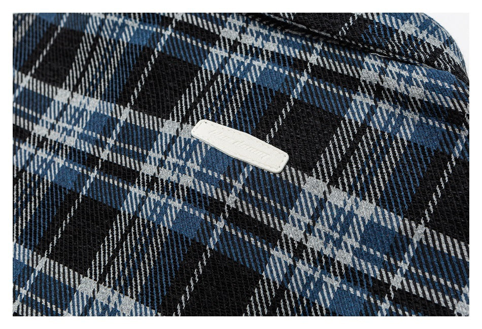 Close-up of blue, black, and gray plaid fabric with a small white rectangular label.