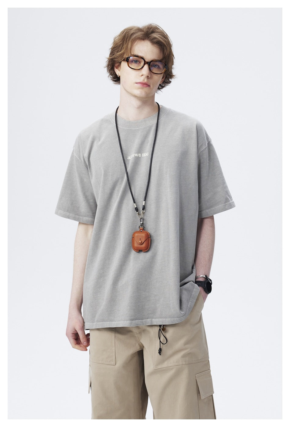 Front view of a model in an oversized light gray T-shirt with small chest text and beige cargo pants.