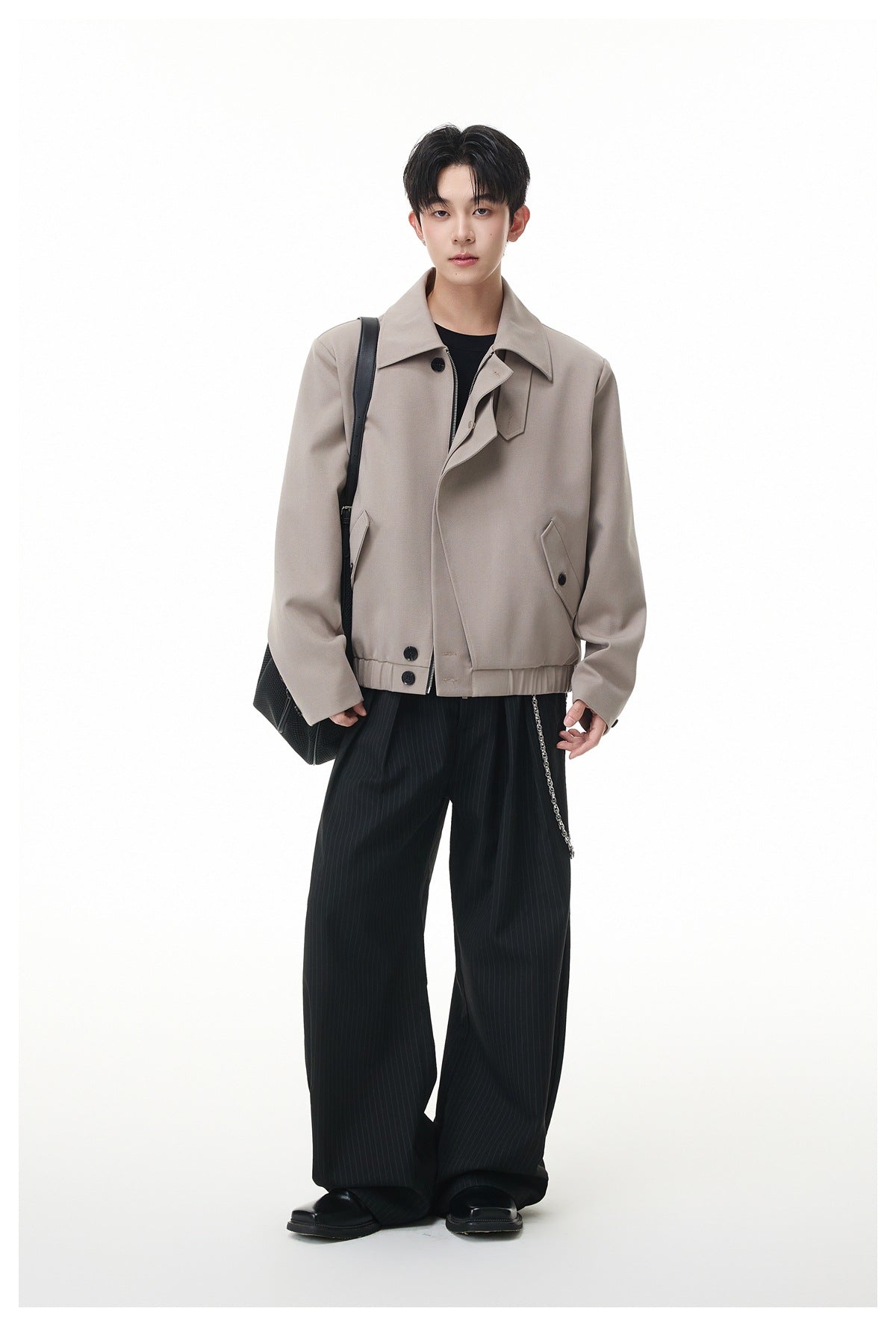 Model standing in a light gray cropped jacket with black pinstripe wide-leg pants, black bag and boots