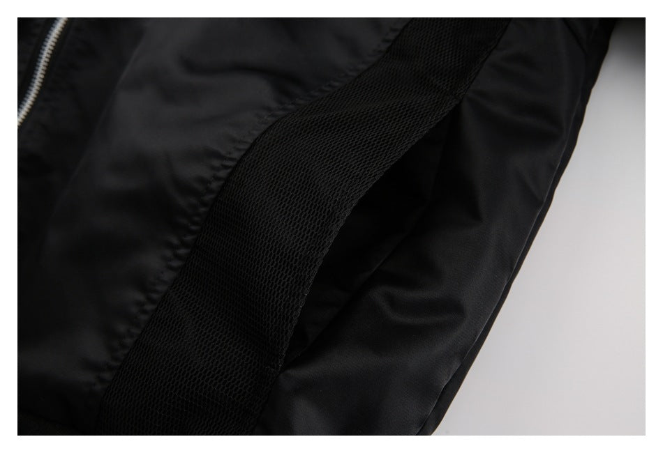 Close-up of a black jacket showing a silver zipper, smooth panels, and a wide black mesh strip.