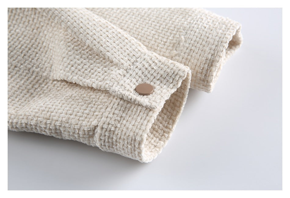 Close-up of an ivory textured jacket sleeve cuff with a snap-fastened tab.