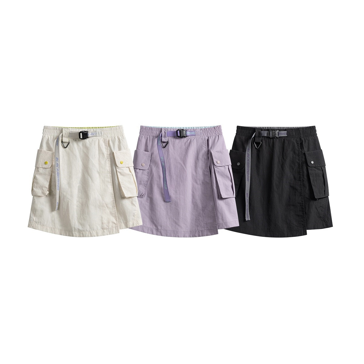 Three utility skirts shown together in off-white, lavender and black, each with a belt and flap cargo pockets.