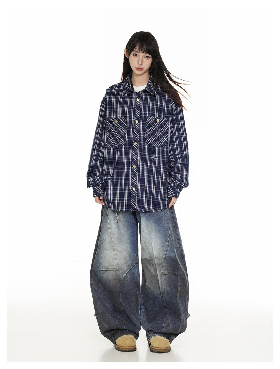 Full-length model wearing an oversized navy plaid button-up shirt and extremely wide, faded blue jeans.