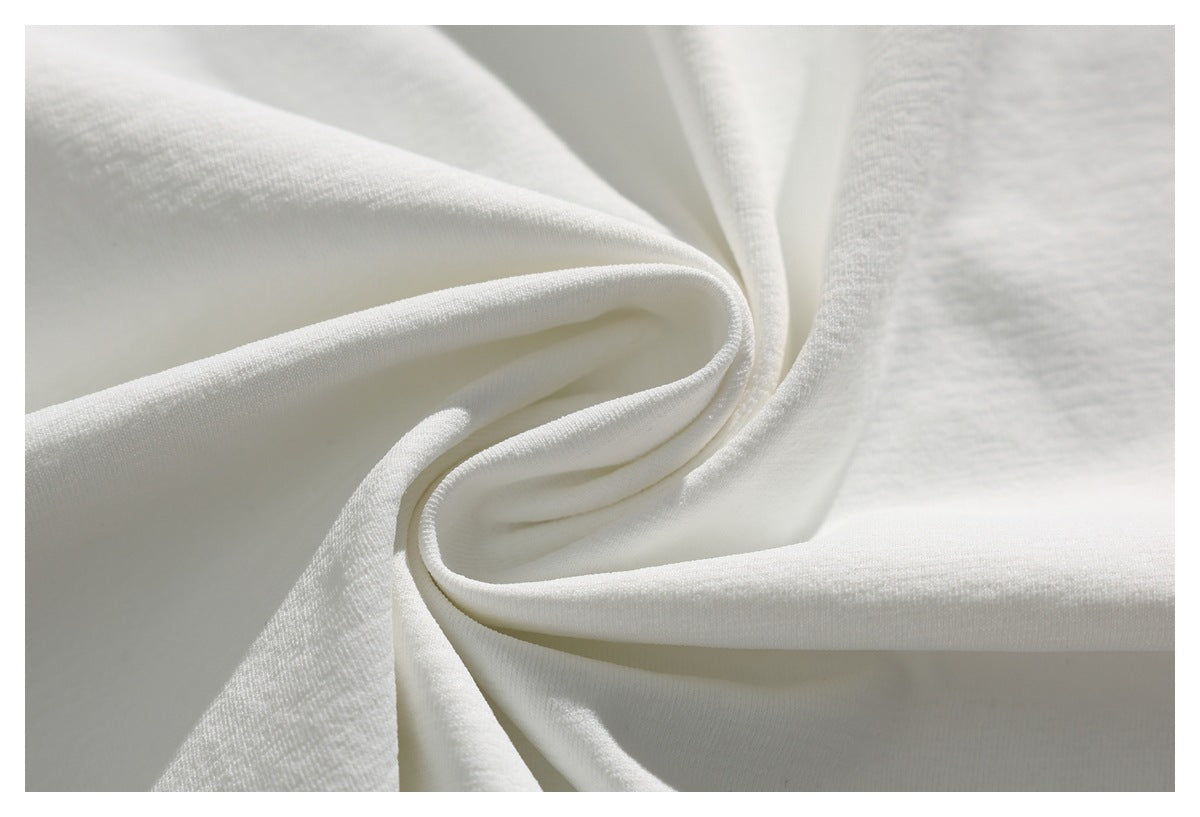 Close-up of white garment fabric gathered into soft folds.