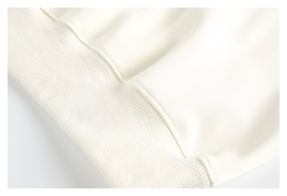 Close-up of an ivory ribbed cuff or hem joined to the smooth garment fabric.
