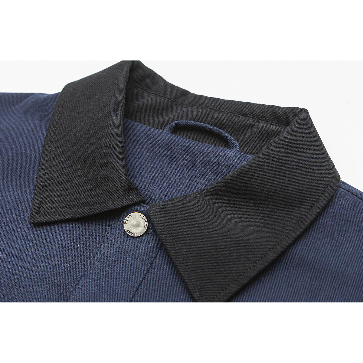 Close-up of a navy jacket with a contrasting black pointed collar and a silver button.