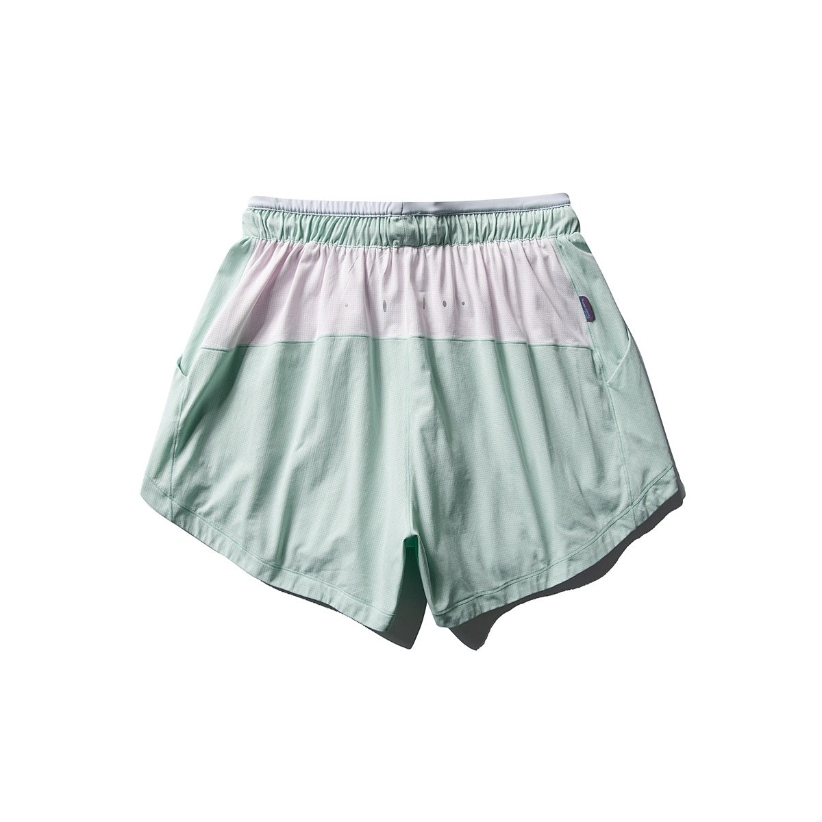 Back view of mint green running shorts with a pale pink upper panel, elastic waistband and curved hems.
