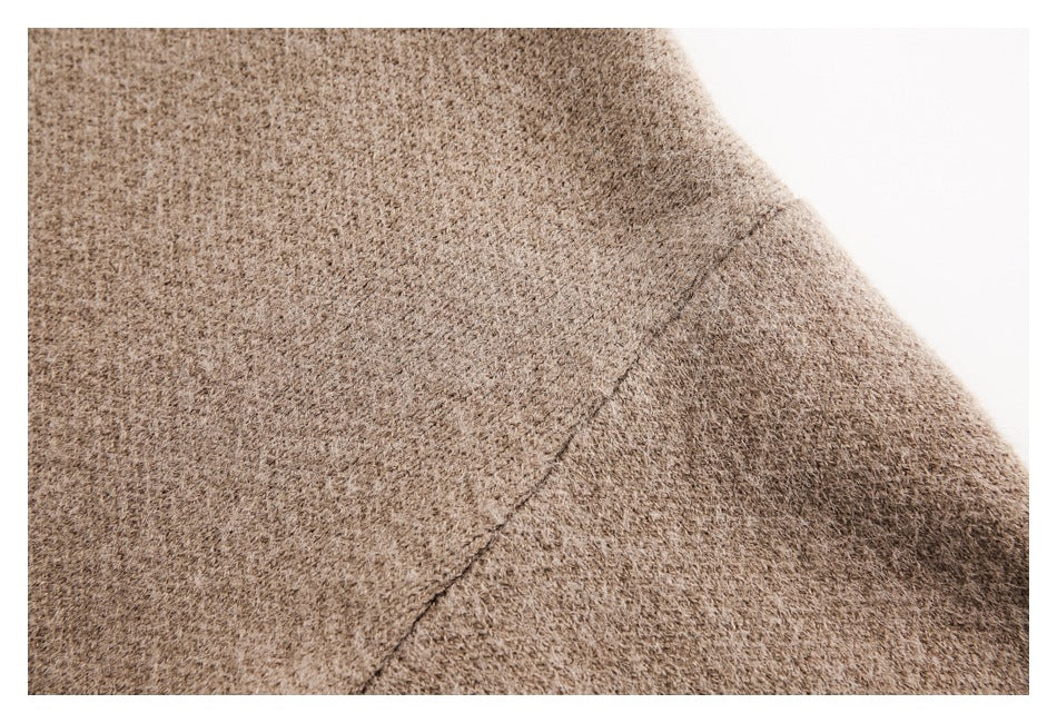 Close-up of a taupe-brown knit garment showing a stitched seam across the textured fabric.