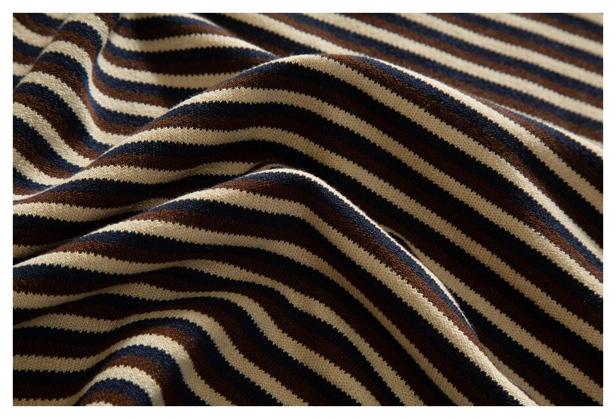 Close-up of draped knit fabric with wavy cream, navy, and brown stripes.