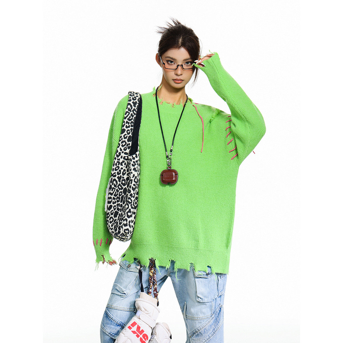 Model wearing an oversized neon-green sweater with pink stitch accents and a distressed hem.