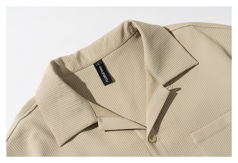 Close-up of a beige ribbed shirt's collar, neckline, button, and chest pocket.