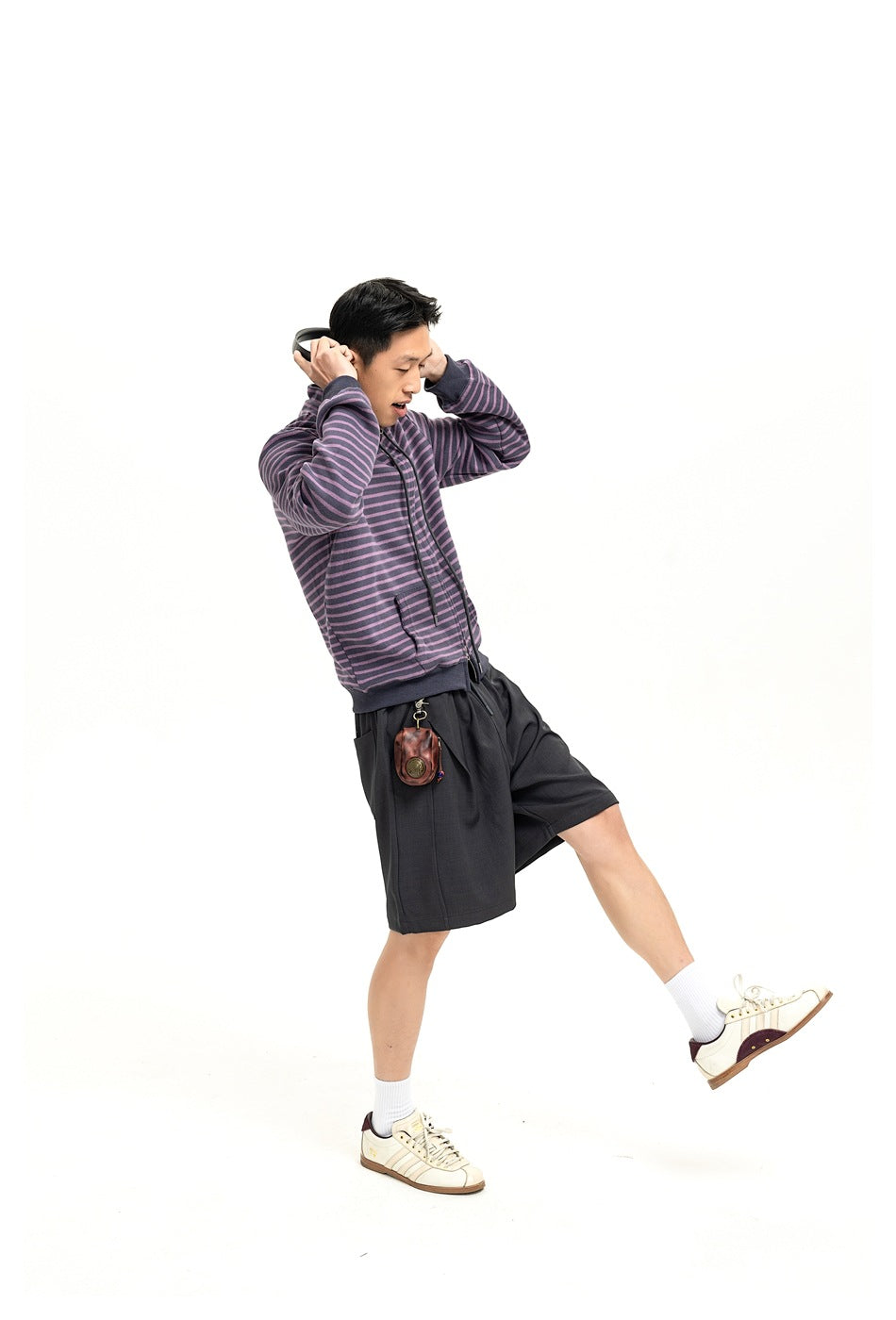 Model wearing a purple and charcoal striped zip jacket and dark shorts in a full-length pose.