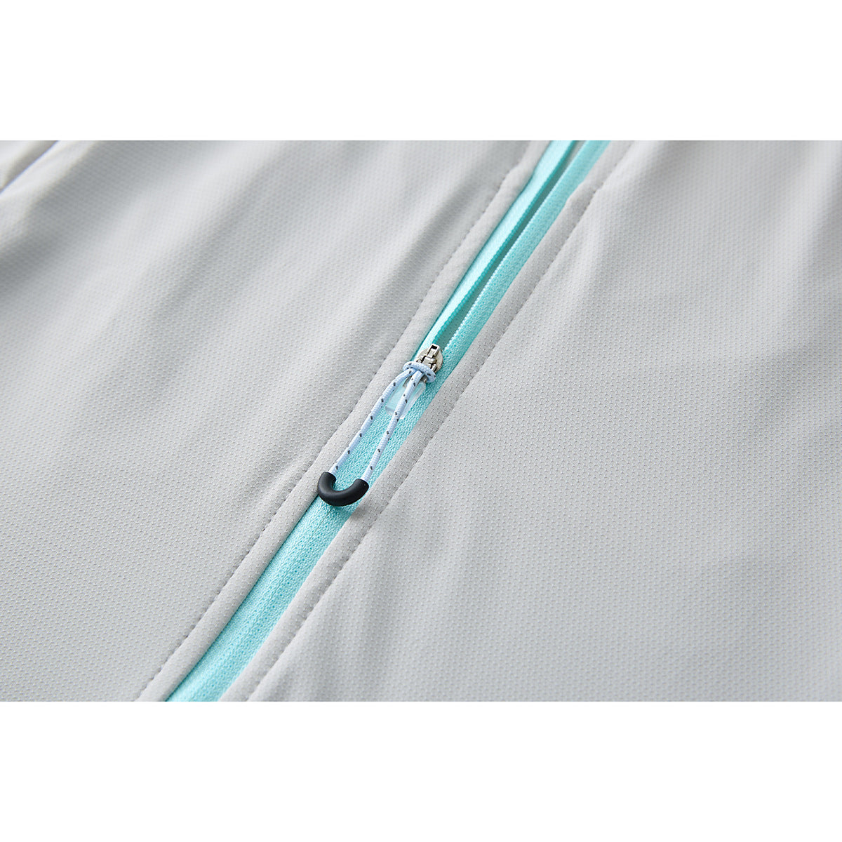 Close-up of a turquoise jacket zipper with a light blue cord pull and black end piece.