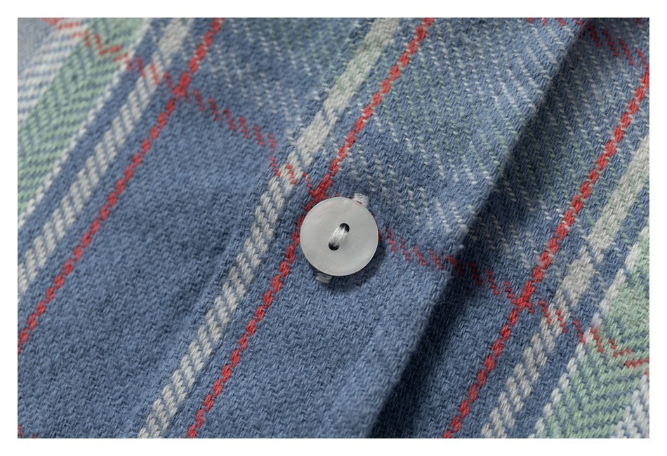 Close-up of a white button on blue plaid shirt fabric.