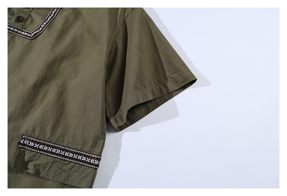 Partial view of an olive short-sleeve shirt showing patterned trim at the neckline and sleeve cuff.